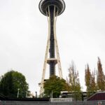 Fencing with colorful patterns made out of yarn. Towering above is the Space Needle.